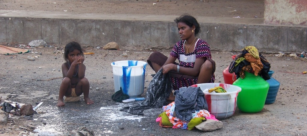 A woman and her daughter wash their clothes in washtubs on the street - Bel