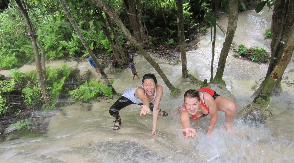 Two women climbing a waterfall in the jungle