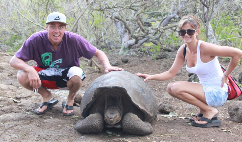 A couple posing with a tortoise on the Galapagos islands