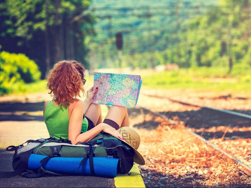 woman looking at a map next to a train line