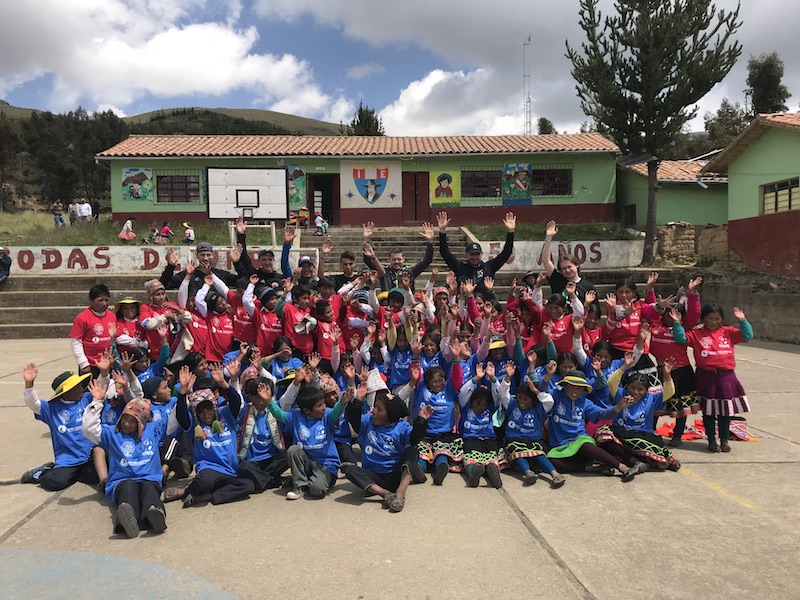 A group of Children and Fotbol for Kids Volunteers throw their hands up in the air. 
