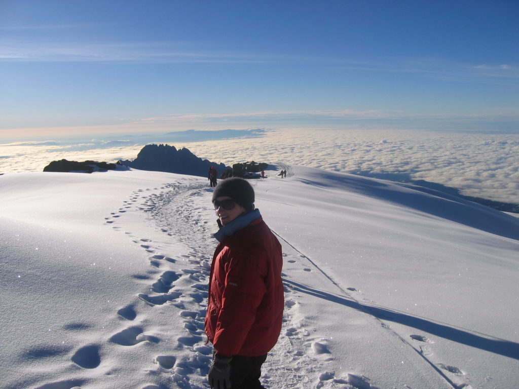 Woman in red jacket standing in snow on Mount Kilimanjaro