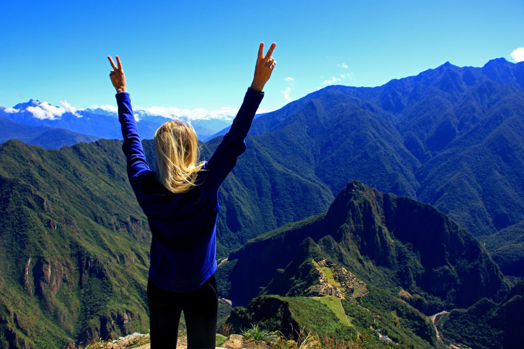 Woman stands in triumph overlooking Machu Picchu