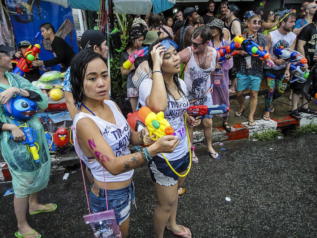 A group of wet people with water guns stand on and next to the road. One of Cambidias weird laws is a ban on water guns
