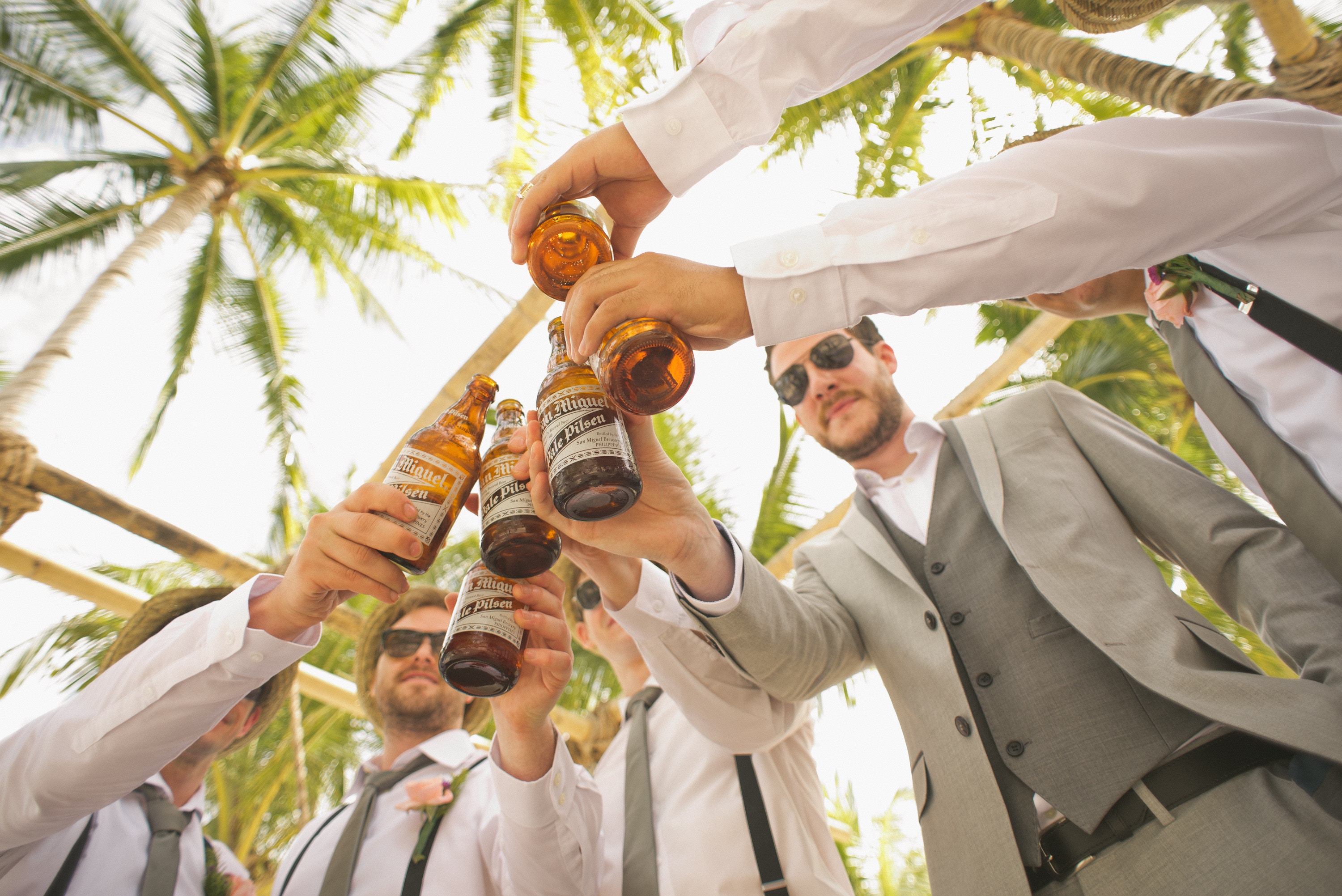 A group of men in suits cheers their bottles of beer