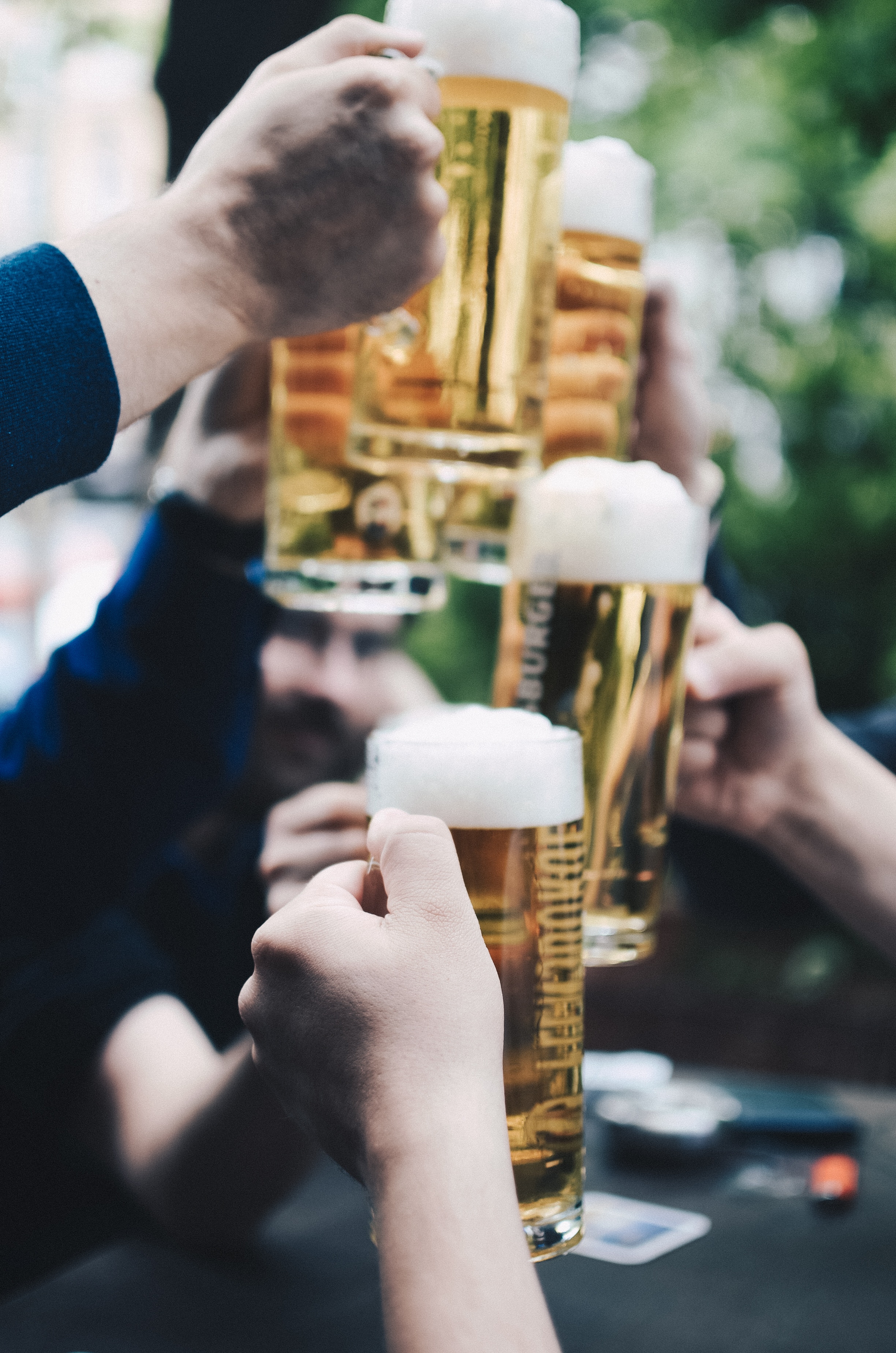 Hands holding steins of foaming beer cheers