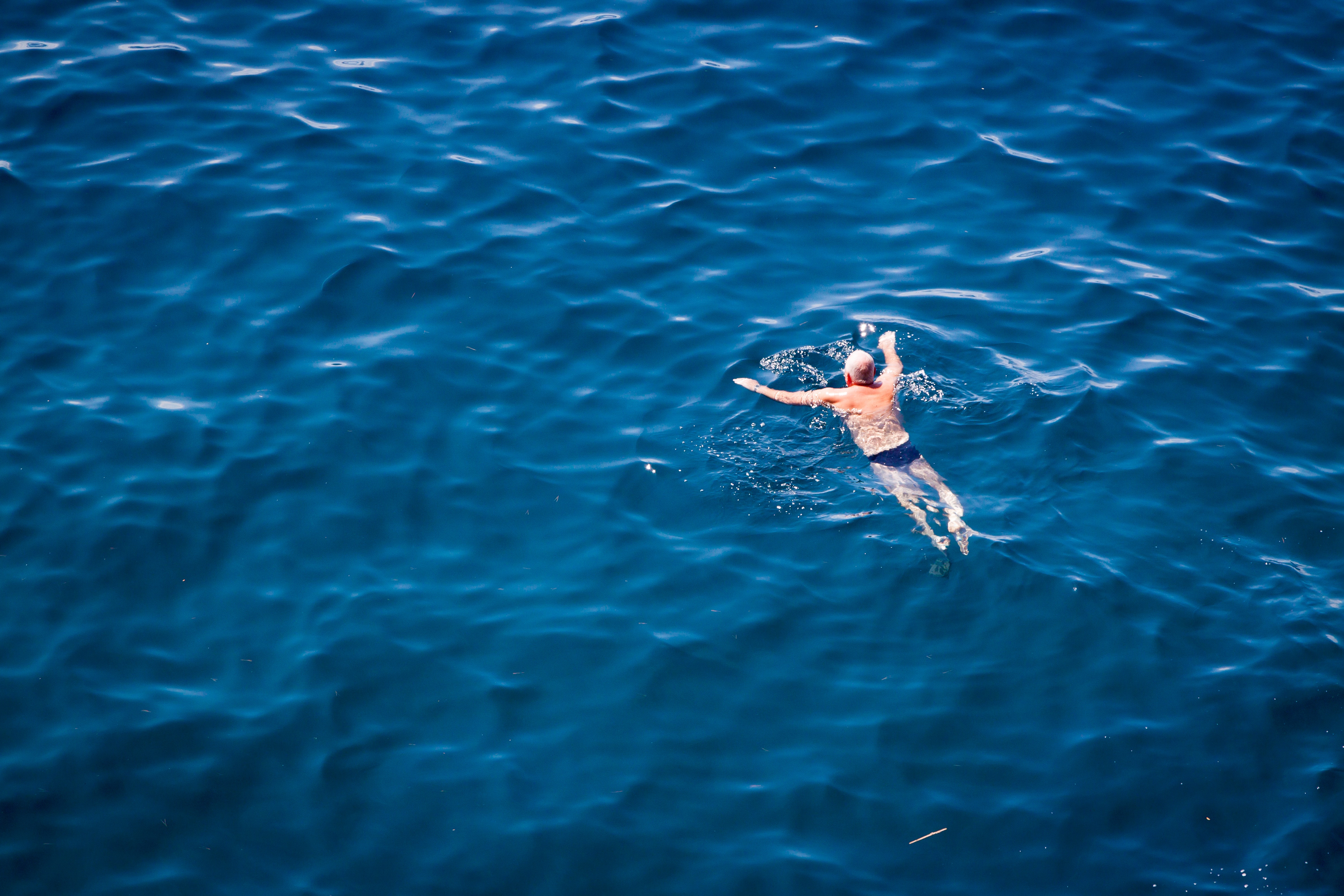 An old man swimming in the ocean in affectionately named "budgey smugglers" in accordance with one of France's wierd laws