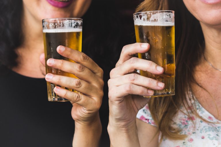 Two women holding full glasses of beer