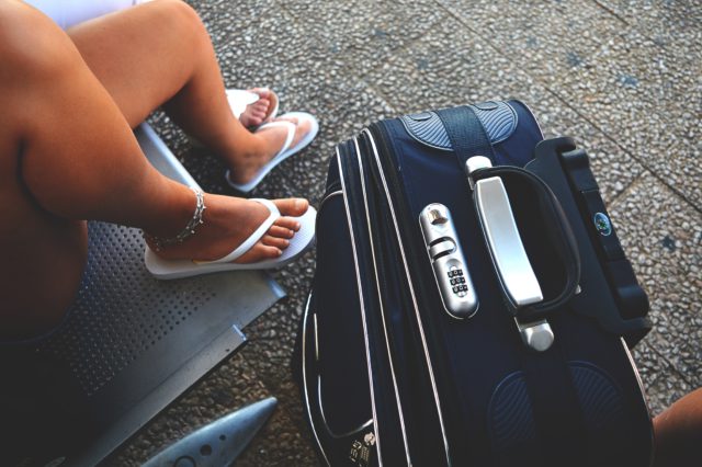 A girls wearing flipflops sitting next to her lugagge