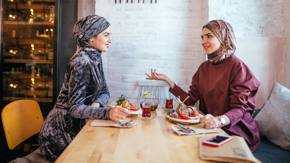 Two Muslim women in cafe, friends meeting
