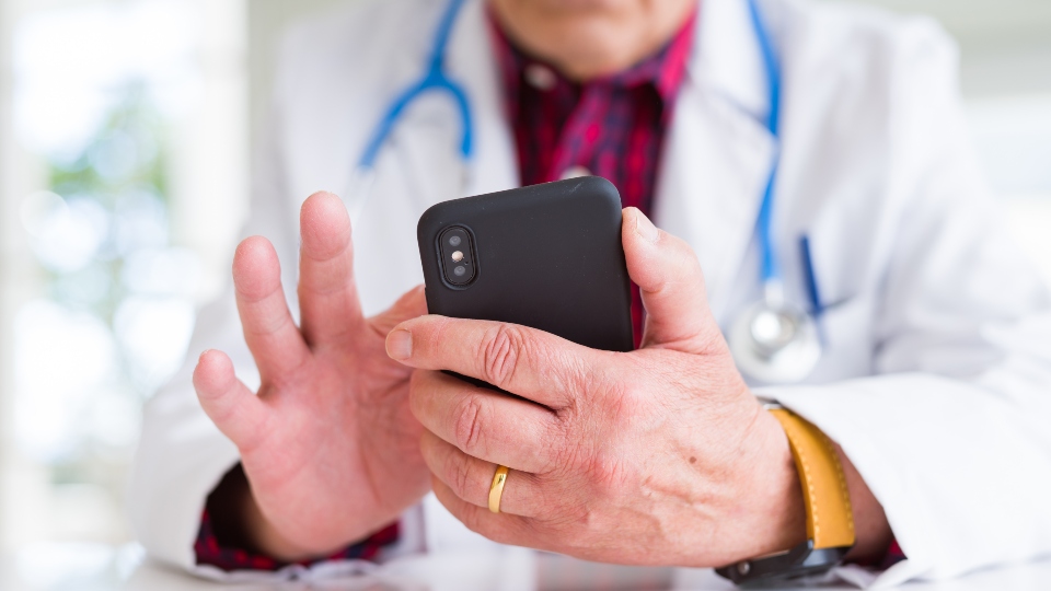 Close up of doctor man hands using smartphone and wearing stethoscope