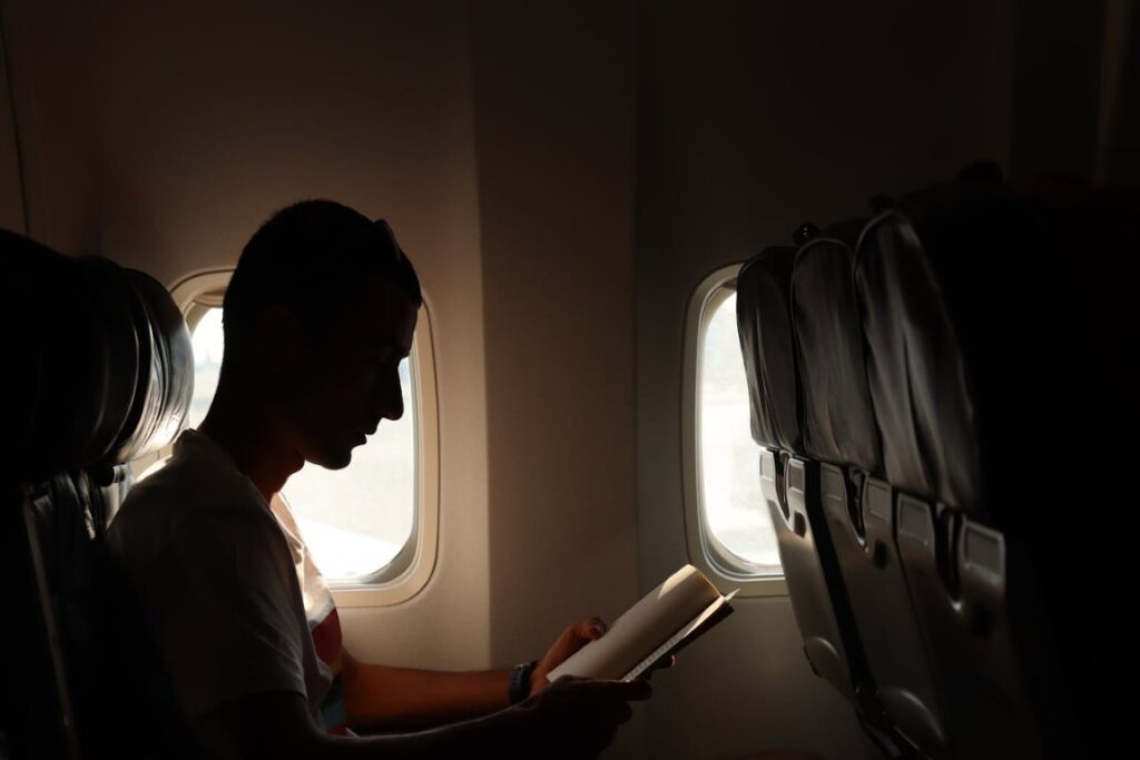man reading a newspaper in plane seat